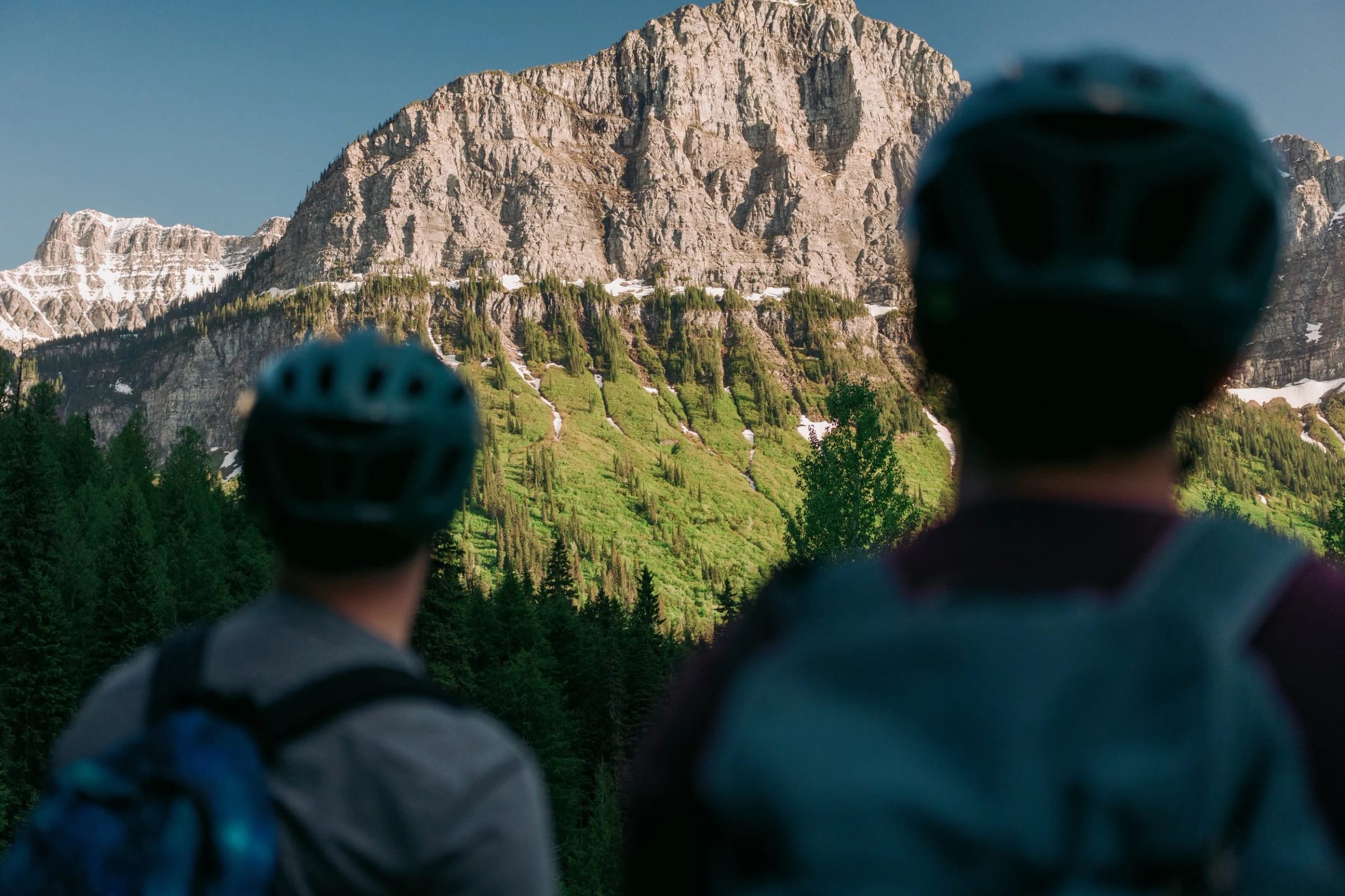 Two riders in helmets looking up at the Garden Wall from the road
