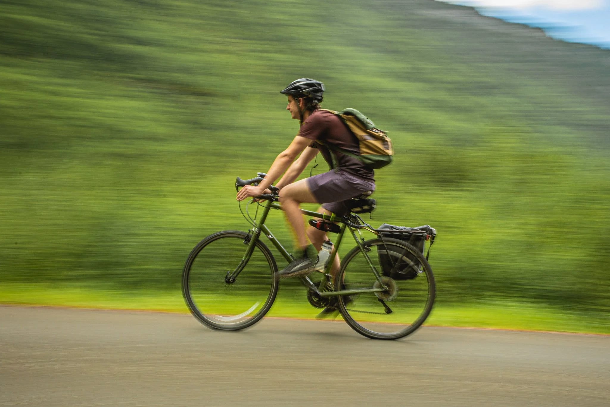 A cyclist with panniers riding a gravel road