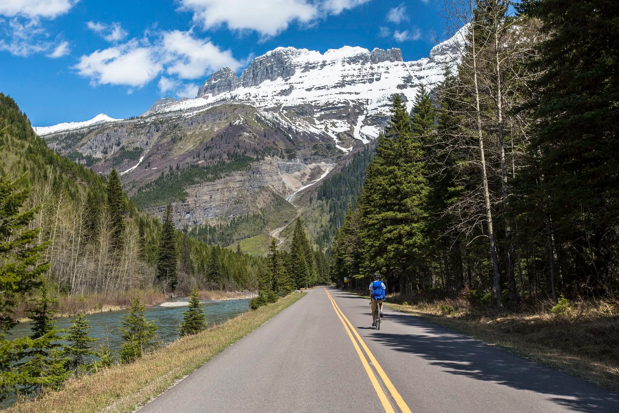 A rider on a mountain road with peaks on both sides