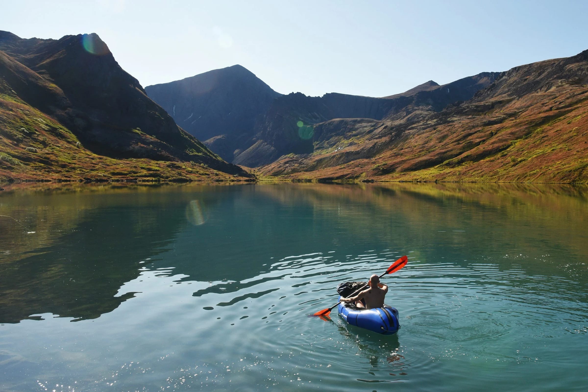 A packraft on a calm lake ringed by peaks