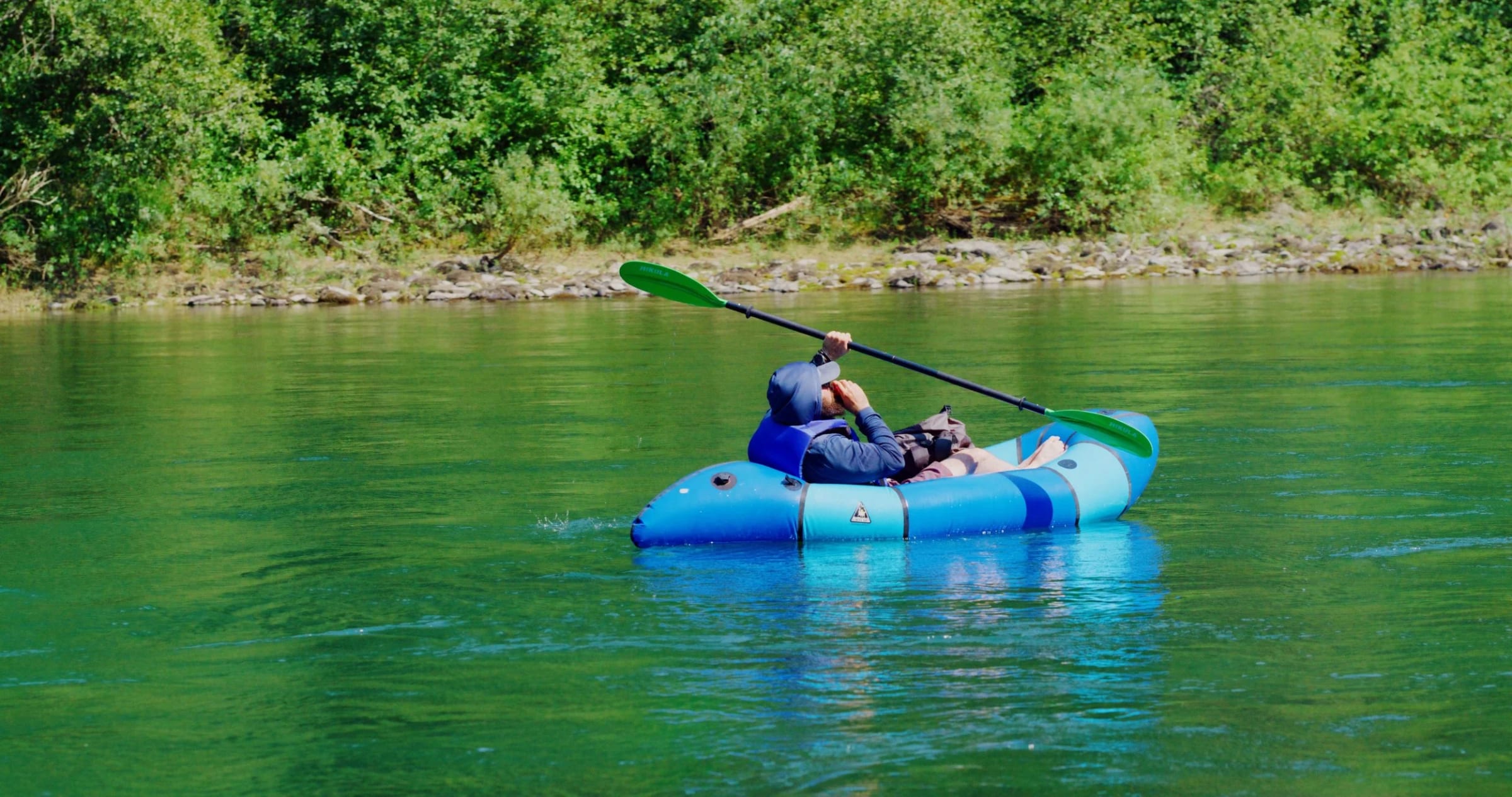 A packrafter paddling green water on the South Fork of the Flathead