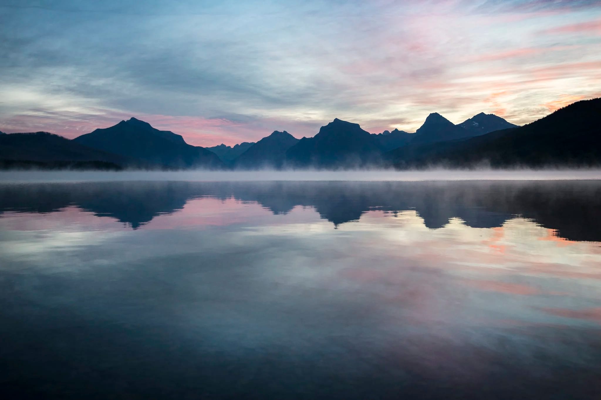 A still lake reflecting the mountains at dawn