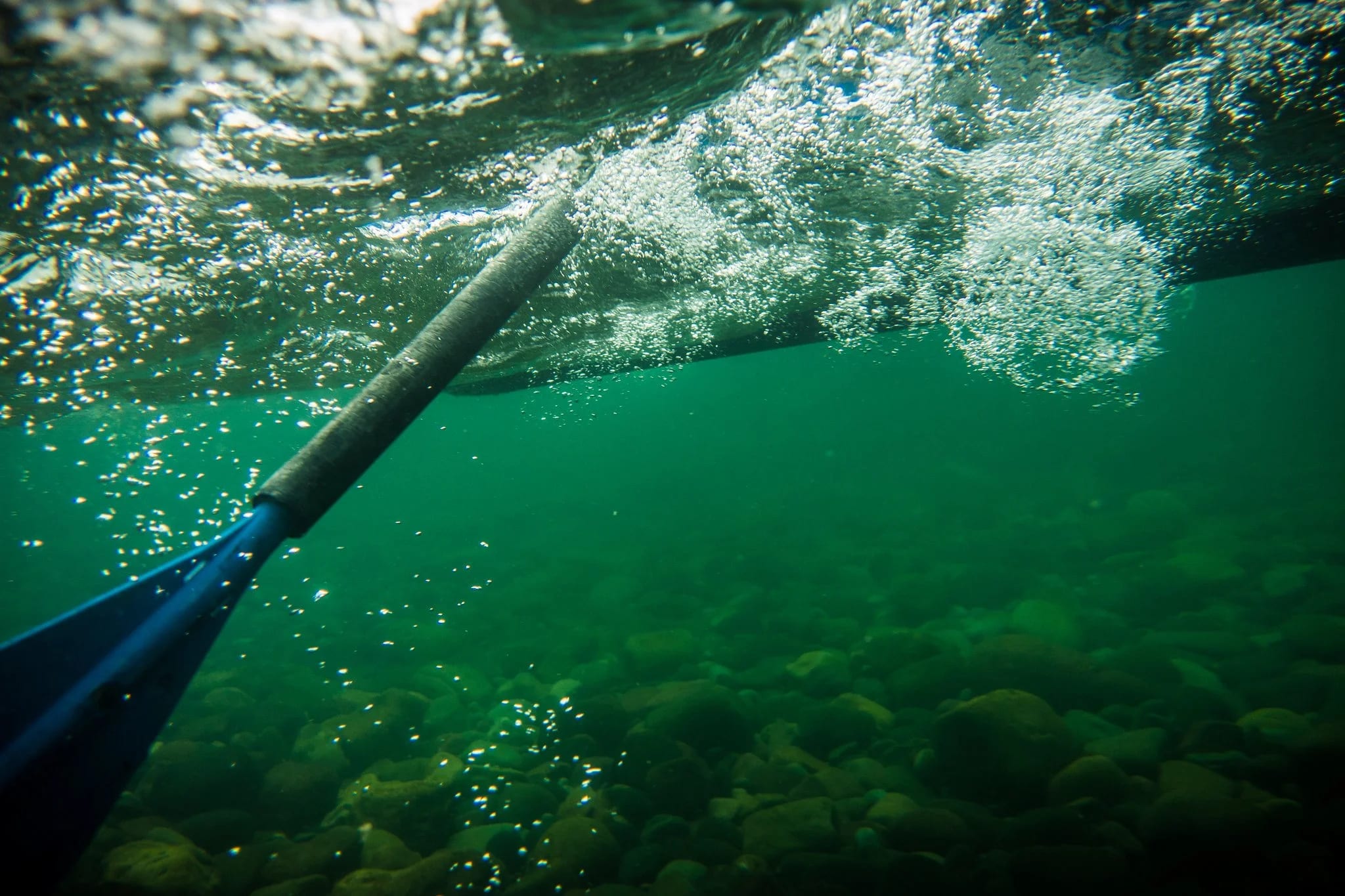 A paddle dipping into clear green water