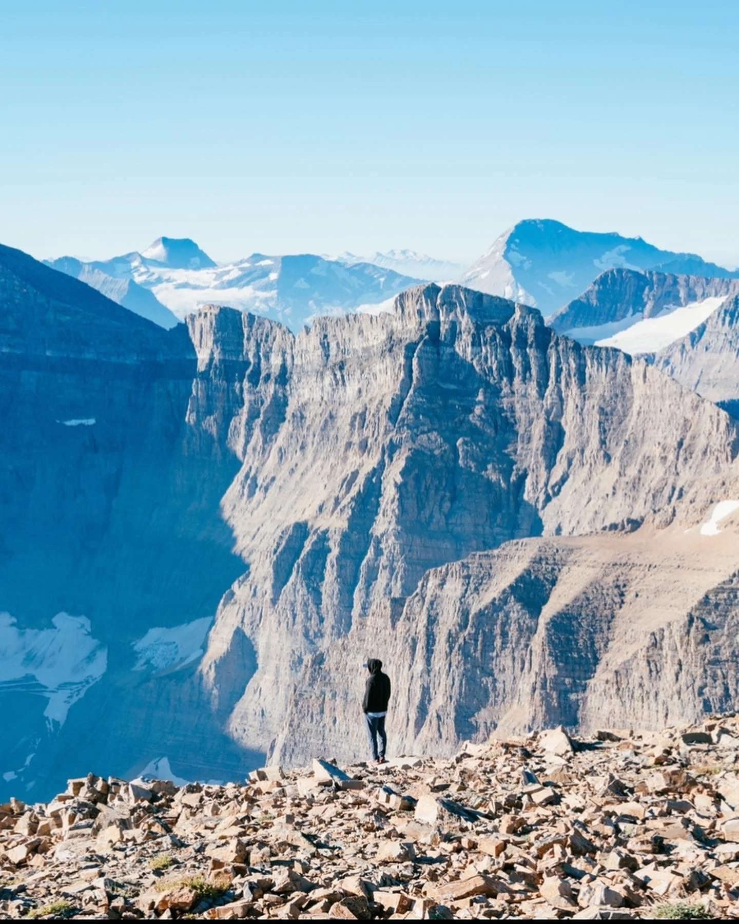 A hiker on rocky ground with mountains behind
