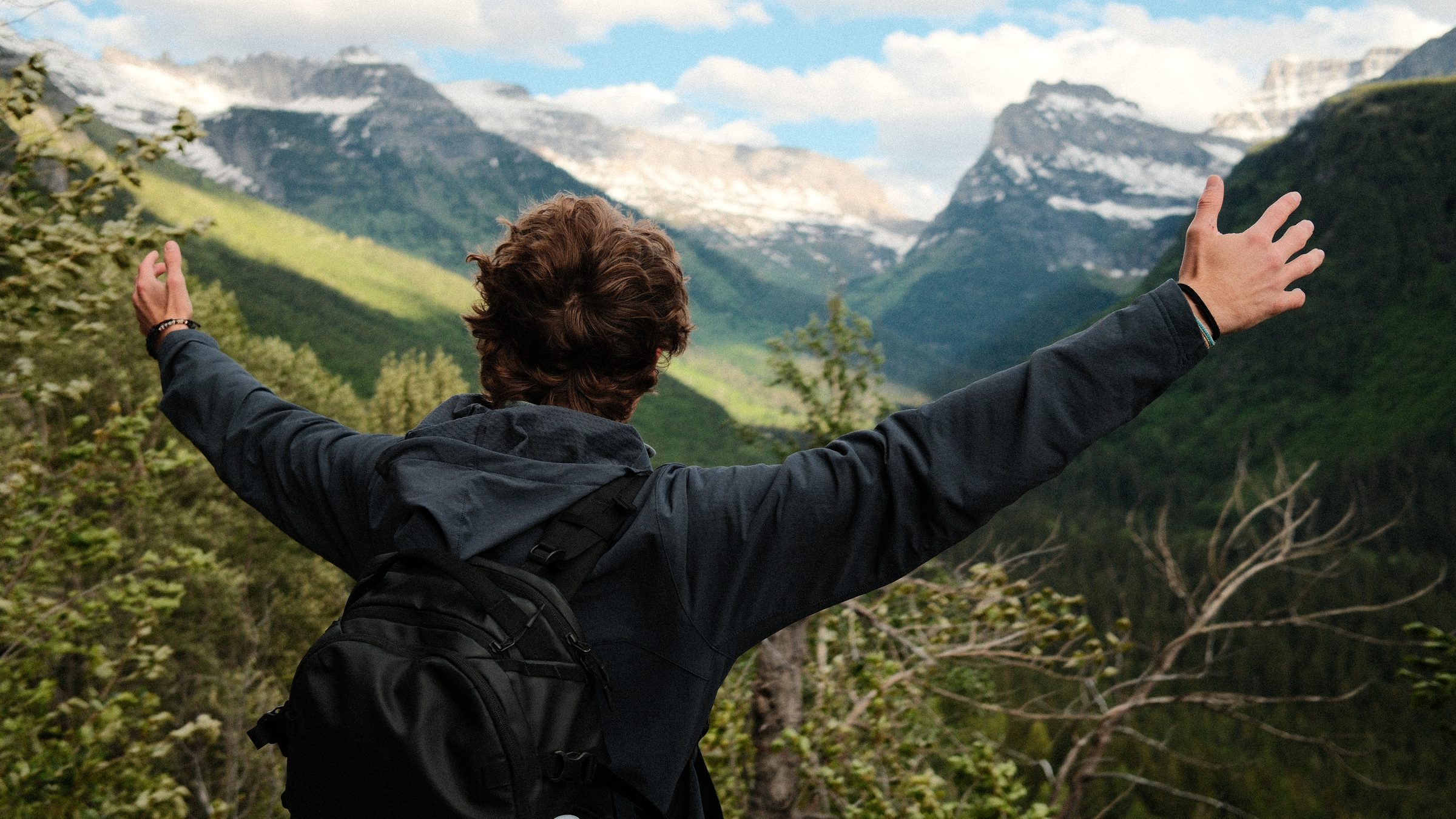 A hiker with arms wide open facing the mountains