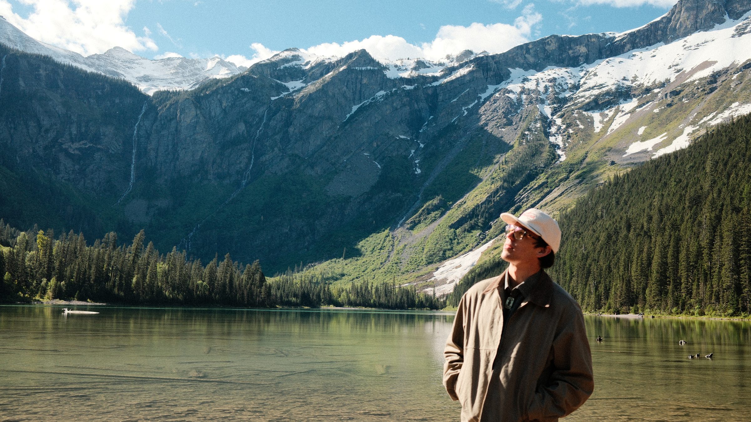 A hiker at an alpine lake below snowy peaks