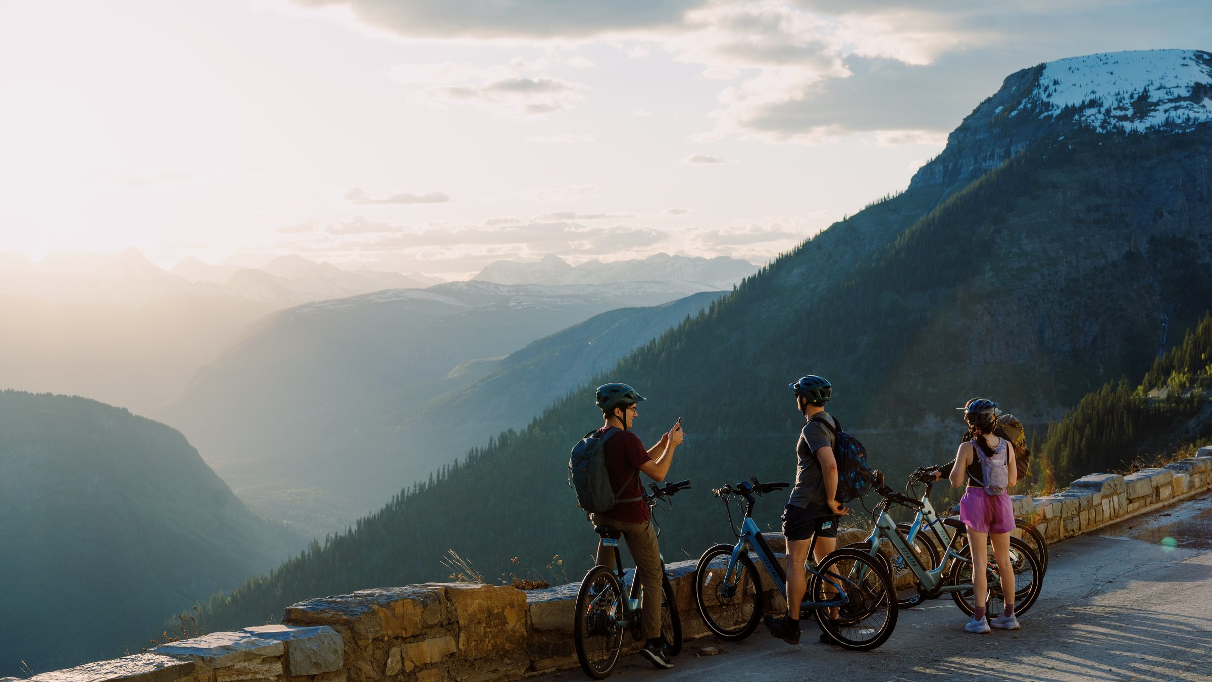 Riders with their e-bikes at an overlook in golden evening light